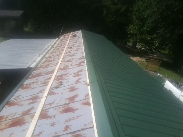 Old rusted panels beside newly installed green metal roofing — Wind Damage Roof Repair by Roofing Brothers in Waco