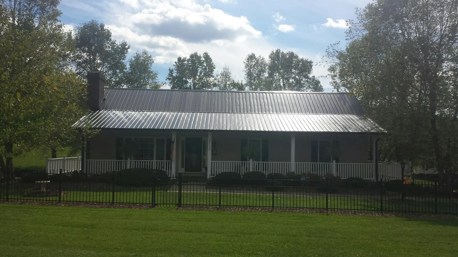 Gray metal roof on a brick ranch with a full width front porch — Gutter Guard Installation work by our crew in Waco